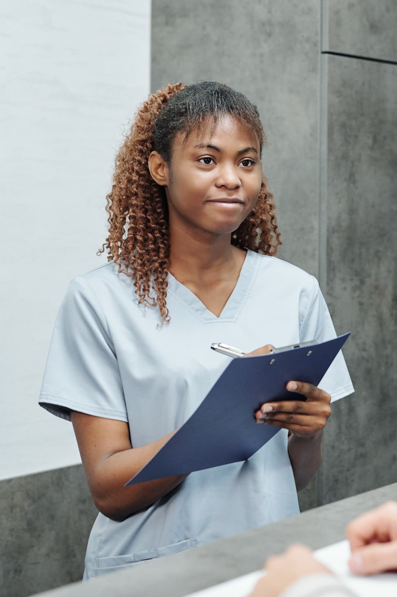 Ein Porträt einer jungen Krankenschwester, die im Patientenzimmer steht.